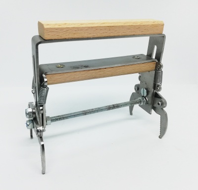 Aparelho metálico com componentes em madeira clara e mola, sobre fundo branco