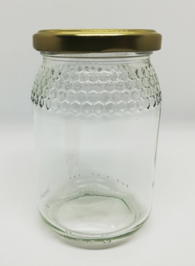 Frasco de vidro transparente com tampa metálica dourada e textura de colmeia