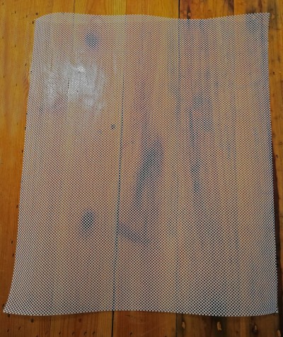 Tela de malha metálica quadrada cinza sobre piso de madeira clara