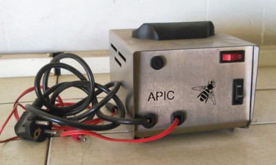 Aparelho metálico cinzento com fios e plugue sobre azulejos