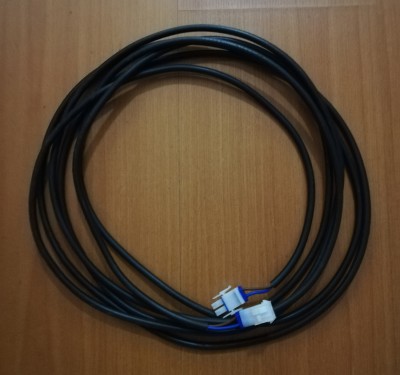 Cabo elétrico preto com conectores brancos sobre madeira clara