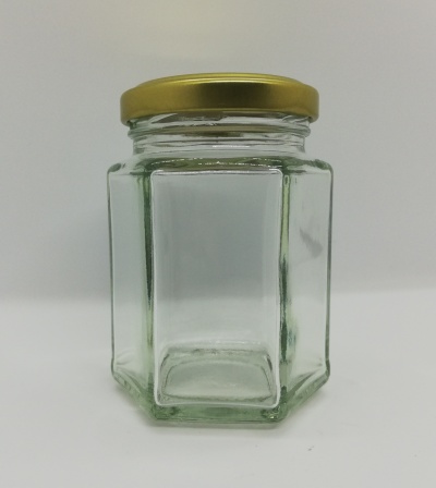 Frasco de vidro hexagonal com tampa dourada, vazio