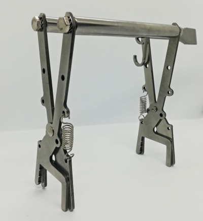 Suporte metálico articulado prateado com molas sobre fundo branco.