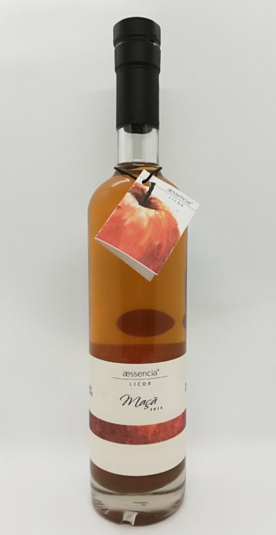 Garrafa de licor de maçã da marca aessencia com etiqueta branca e etiqueta pendurada com imagem de maçã.