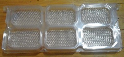 Embalagem plástica transparente com seis compartimentos hexagonais sobre fundo de madeira