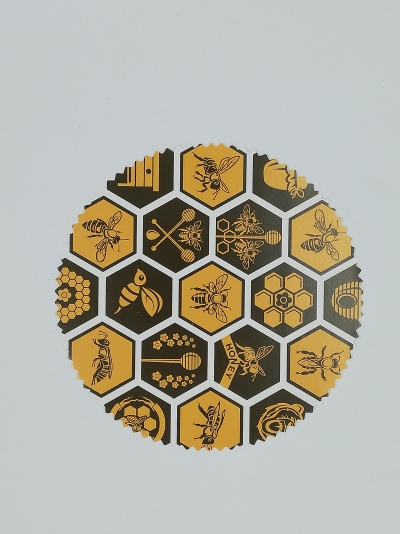 Disco redondo com ilustrações de abelhas e favos de mel em hexágonos amarelos e pretos