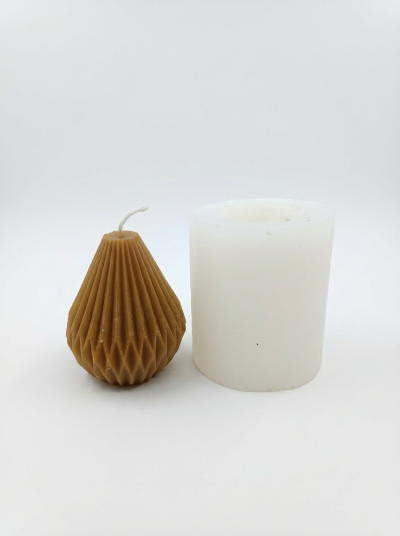 Dois velas, uma castanha facetada em forma de gota e uma branca cilíndrica sobre fundo branco