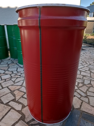 Barril metálico vermelho com rebordo prateado num piso de mosaico exterior.