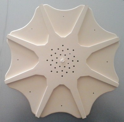 Objeto branco circular com oito secções e furos no centro sobre superfície cinzenta