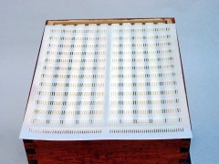 Caixa de madeira com uma capa branca perfurada por cima