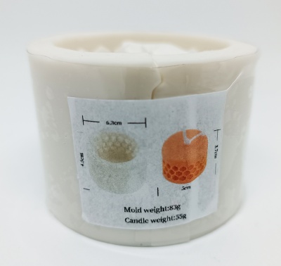 Vela branca circular com etiqueta mostrando molde e vela laranja com padrões hexagonais