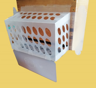 Caixa branca de papelão com orifícios e aba cinzenta sobre fundo amarelo