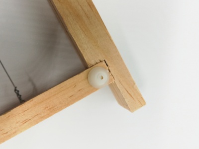 Peça de madeira clara com pino plástico branco em fundo branco