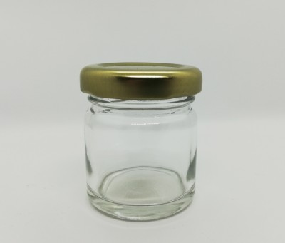 Frasco pequeno de vidro com tampa dourada sobre fundo branco