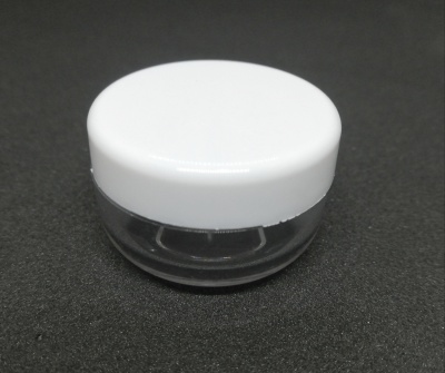 Recipiente pequeno transparente com tampa branca sobre fundo preto