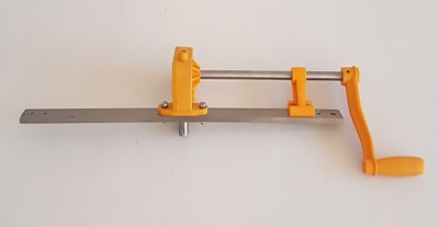 Ferramenta manual metálica com manivela laranja montada numa parede branca