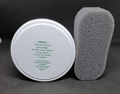 Frasco branco de cera de abelhas CERAPIEL e esponja cinzenta sobre superfície escura