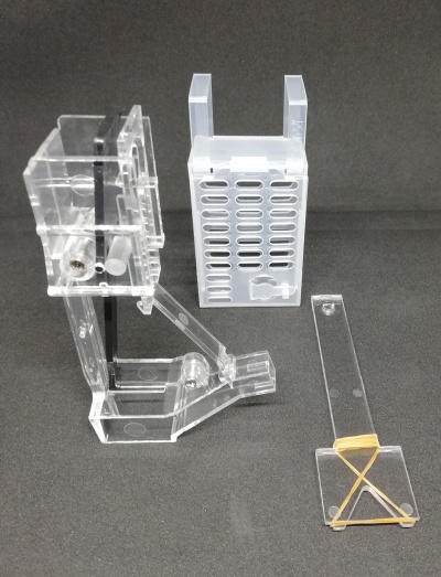 Peças de acrílico transparente com componentes metálicos e elásticos sobre fundo preto