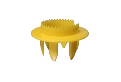 Peça plástica amarela com dentes e quatro pernas sobre fundo branco