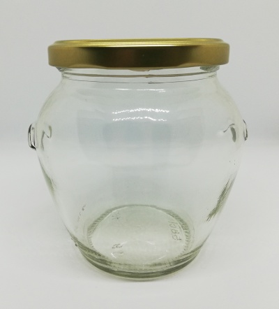 Frasco de vidro com tampa dourada sobre superfície branca