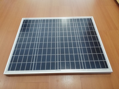 Painel solar fotovoltaico com células azuis e moldura branca sobre chão de madeira