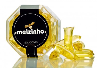 Embala gem octogonal com cápsulas de mel amarelas e etiqueta preta com texto em branco