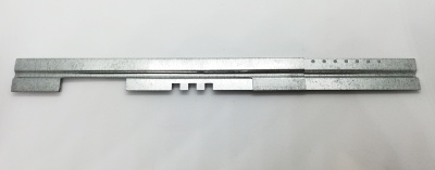 Peça metálica cinza com perfis e furos sobre fundo branco