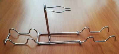 Suporte metálico prateado com formas onduladas em superfície de madeira clara