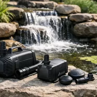 Bombas de água pretas e acessórios numa pedra junto a um lago com cascata e plantas aquáticas