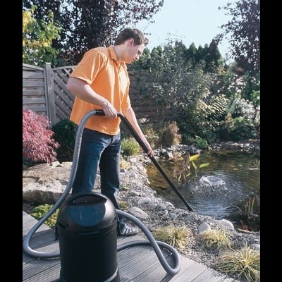 Homem a usar aspirador de pó preto para limpar perto de lago artificial exterior