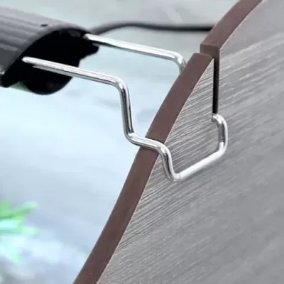 Suporte metálico preto preso a um painel de madeira cinzento com bordas castanhas