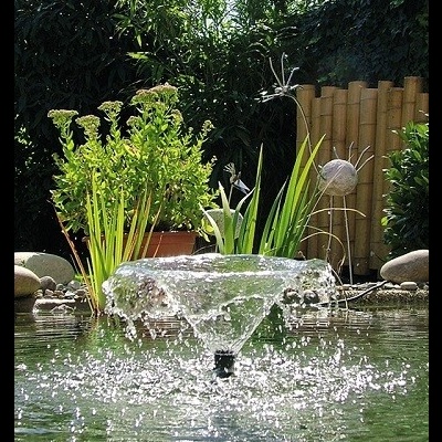 Fonte de água em jardim com plantas verdes e pedras decorativas
