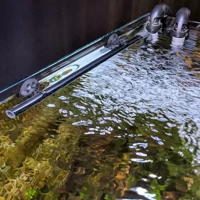 Superfície de vidro com água e tubos pretos de suporte
