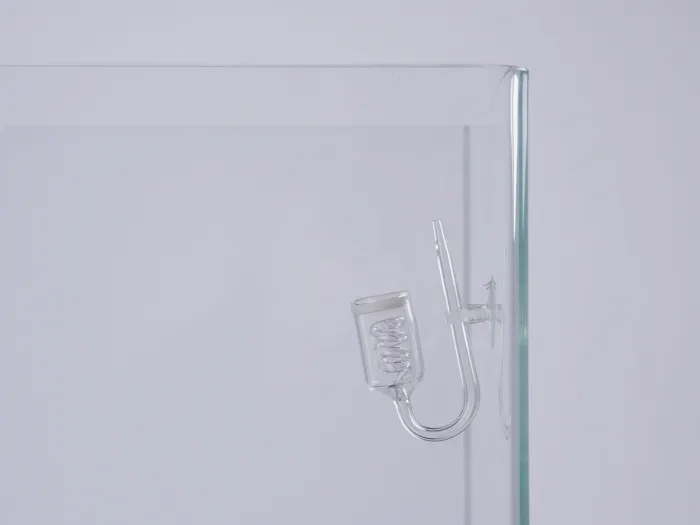Acessório de vidro transparente com tubo em U e bobina, fixado à aresta de um recipiente de vidro maior