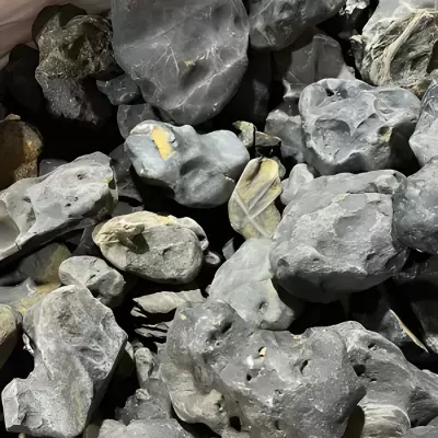 Pedras rugosas cinza com manchas amarelas empilhadas em pilha