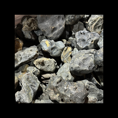 Pedras cinzentas irregulares com manchas amarelas empilhadas.