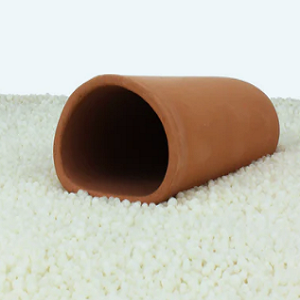 Vaso oval de cerâmica castanho claro sobre pequenas esferas brancas.