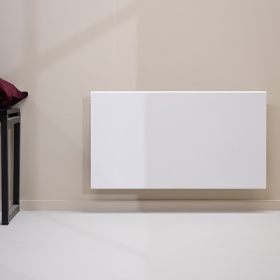 Radiador branco numa parede bege clara com banco preto e almofada bordô