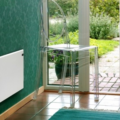 Radiador branco numa parede verde com cadeira transparente e porta aberta para jardim