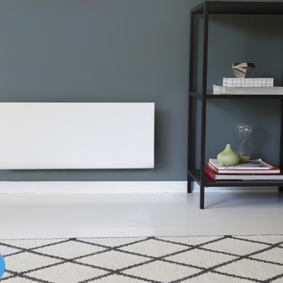 Radiador branco na parede cinzenta com prateleira preta e livros