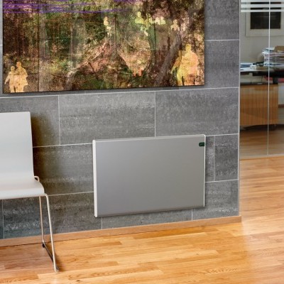 Radiador elétrico cinza claro numa parede de azulejos cinzentos ao lado de uma cadeira branca e pintura colorida