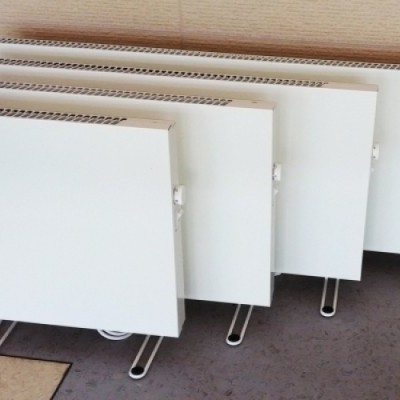 Quatro radiadores eléctricos brancos de painel com suportes metálicos prateados
