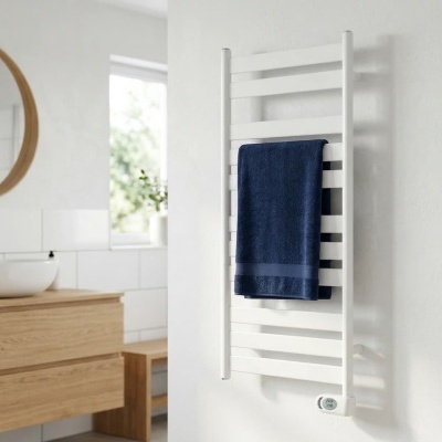 Toalheiro eléctrico branco com toalha azul escura numa casa de banho moderna