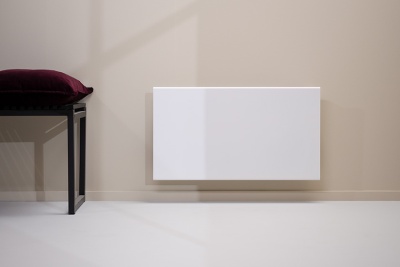 Radiador branco numa parede bege clara com banco preto e almofada bordô