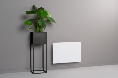 Radiador branco na parede cinzenta com planta verde em vaso preto ao lado