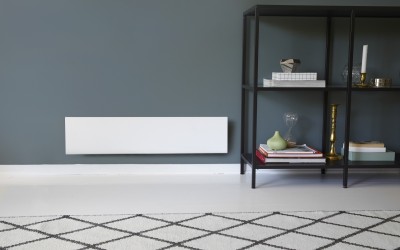 Radiador elétrico branco montado na parede cinzenta com estante preta ao lado