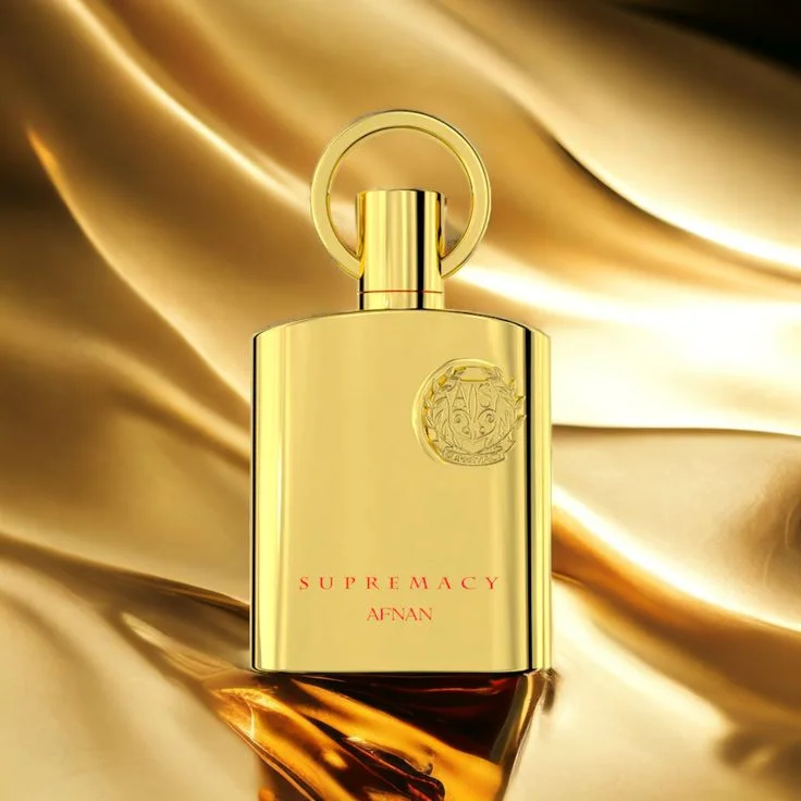 Frasco de perfume dourado SUPREMACY AFNAN sobre tecido cetim dourado