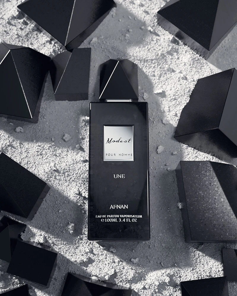 Frasco de perfume preto Modest pour homme com tampas pretas ao redor em fundo cinza