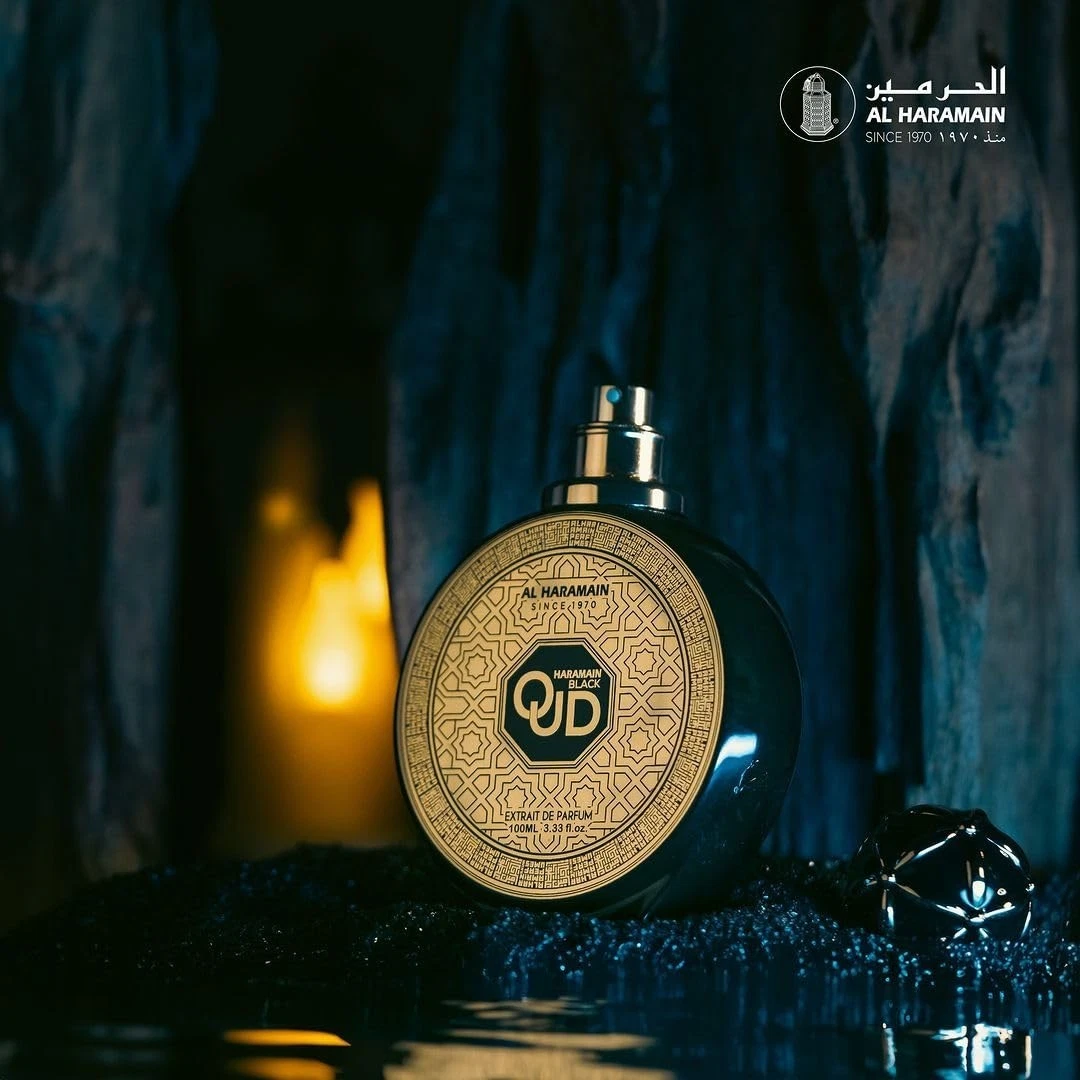 Frasco preto redondo de perfume Al Haramain Oud com rótulo dourado e vela ao fundo