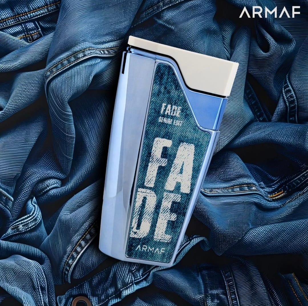 Frasco de perfume azul com tampa branca e etiqueta azul jeans sobre tecido de ganga azul.